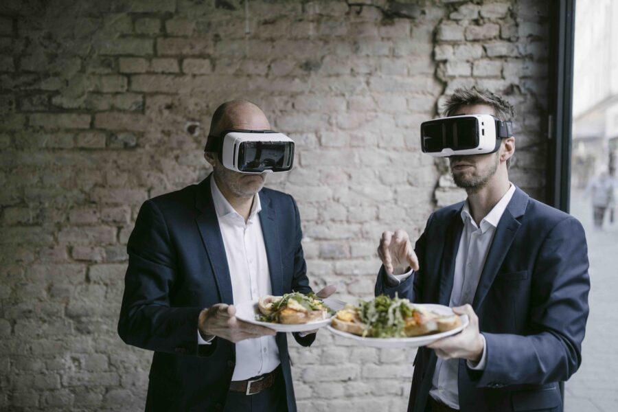 Senior and mid-adult businessman wearing VR glasses holding plate with a meal